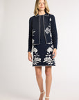 Woman modeling a black jacket with fern detailing on the front in a studio
