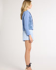 A woman modeling a light blue jacket with fern detailing and collar on a white background