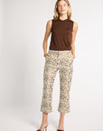 A woman modeling a sleeveless brown mock-neck top and patterned cropped pants with a brown leopard print, paired with dark brown pointed-toe heels, against a light gray studio background.