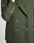Close-up of a dark olive green double-breasted blazer with silver buttons, worn by a model.