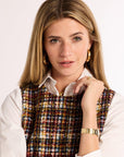 Headshot of woman wearing a plaid tweed dress with a white shirt on a white background with gold jewelry