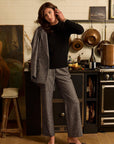 Woman in a checkered blazer and pants standing in a kitchen.