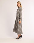 Profile angle of woman wearing a grey and white checkered flannel dress on a white background