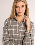 Portrait angle of woman wearing a gray and white checkered flannel dress against a plain background