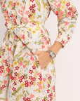 Floral patterned dress with a belt on a plain background