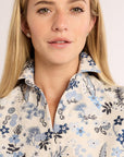 Woman wearing a floral patterned shirt against a plain background