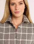 Woman wearing a gray and white checkered shirt against a plain background