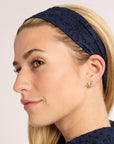Woman wearing a navy blue lace headband against a plain background