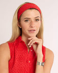 Woman wearing a red headband and shirt against a plain background