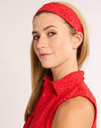 Woman wearing a red headband and sleeveless top against a light background