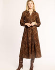 Woman wearing a brown patterned dress and boots on a white background