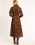 Woman wearing a brown paisley patterned coat on a white background