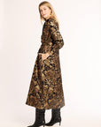 Woman wearing a long black and gold floral dress on a white background