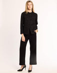 Woman wearing a black textured jacket in heels on a white background