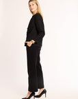 Woman wearing a black textured jacket and black pants on a white background