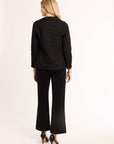 Woman wearing a black textured blazer and black pants on a white background