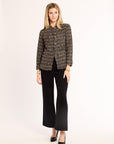 Woman wearing a patterned jacket and black pants on a white background