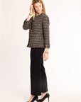 Woman wearing a patterned jacket and black pants on a white background