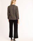 Woman wearing a tweed jacket and black pants on a white background