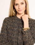 Woman wearing a textured brown sweater with a plain background