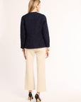 Woman wearing a navy blue blazer and beige pants on a white background