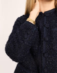 Navy blue textured coat with a gold watch on a neutral background
