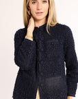 Woman wearing a navy textured jacket on a light background