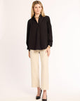 Woman wearing a black shirt and beige pants on a white background