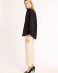 Woman wearing a black shirt and beige pants on a white background