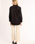 Woman wearing a black shirt and beige pants on a white background