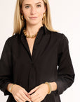 Woman wearing a black shirt with gold jewelry on a white background