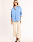 Woman wearing a light blue shirt and beige pants on a white background