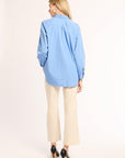Woman wearing a light blue shirt and beige pants on a white background