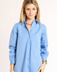 Woman wearing a light blue button-up shirt against a plain background