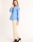 Woman wearing a light blue shirt and beige pants on a white background