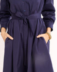 Navy blue dress with a belt and long sleeves on a white background