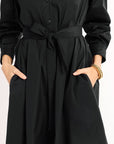 Black dress with a belt worn by a person on a white background