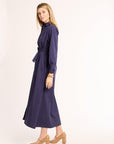 Woman wearing a long-sleeve, long navy dress on a white background
