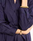 Navy blue shirt with a tie waist worn by a person, with gold bracelets on wrists.