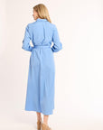Woman wearing a light blue dress with a belt on a white background