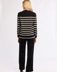 Person wearing a black and white striped sweater and black pants on a white background