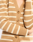 Close-up of a person wearing a white and beige striped cardigan with buttons.