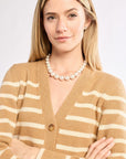 Woman wearing a beige and white striped sweater with a pearl necklace on a white background
