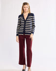 Woman wearing a striped cardigan and burgundy pants on a white background