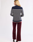 Woman wearing a navy and white striped sweater with red pants on a white background
