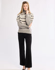 Woman wearing a gray patterned sweater and black pants on a white background