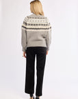 Person wearing a patterned sweater and black pants on a white background