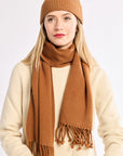 Woman wearing a brown knit hat and scarf on a white background