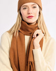 Woman wearing a brown knit hat and scarf on a white background