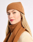 Woman wearing a brown knit hat and scarf on a white background